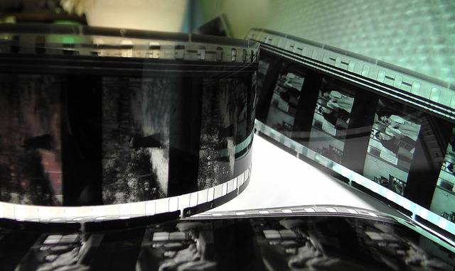 Close-up of black and white film strips, showing various frames and details, laid out on a reflective surface.